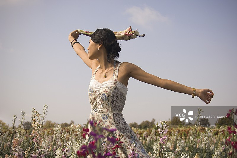 在草地上张开双臂的穿着太阳裙的女人图片素材