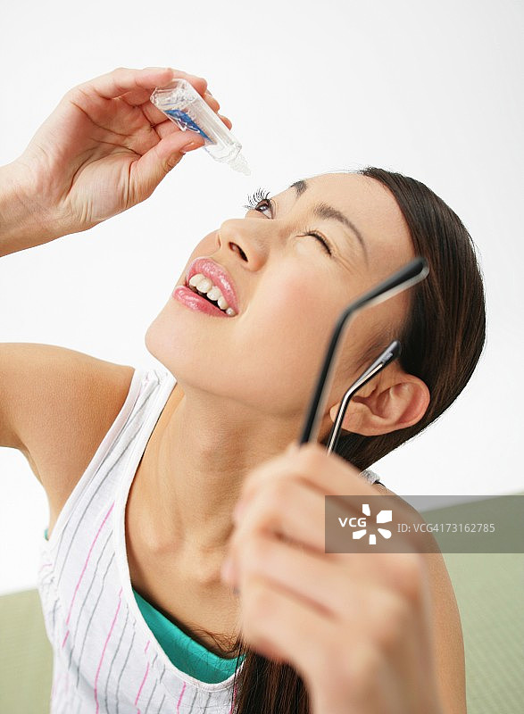 亚洲年轻女人正在滴眼药水图片素材