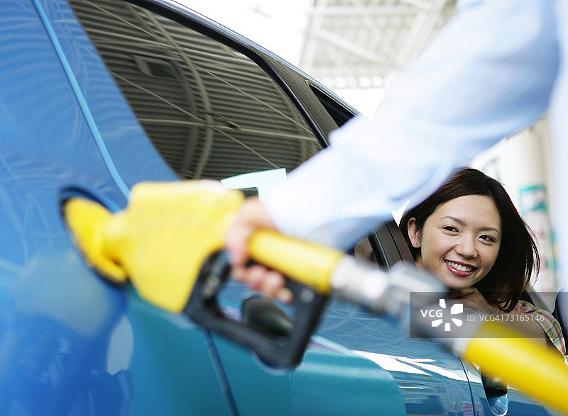 女人看着男人拿着汽油泵喷嘴图片素材
