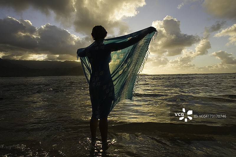 肩披纱笼站在海滩上的女子图片素材