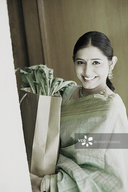 微笑着手提购物袋的年轻女人肖像图片素材