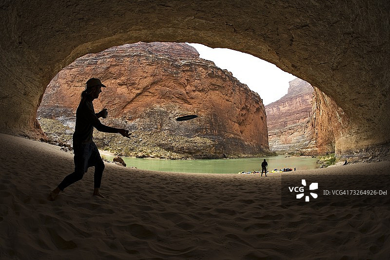 男人在亚利桑那州大峡谷的大洞穴中扔飞盘图片素材