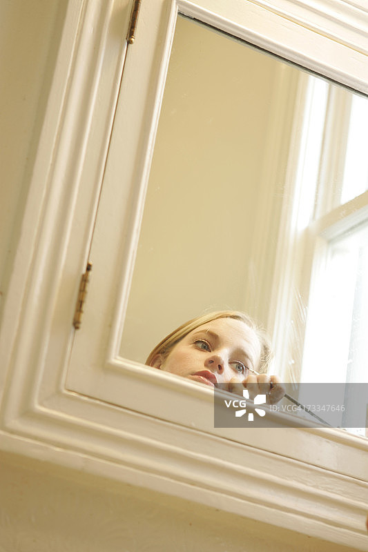 在浴室镜子前化妆的少女图片素材