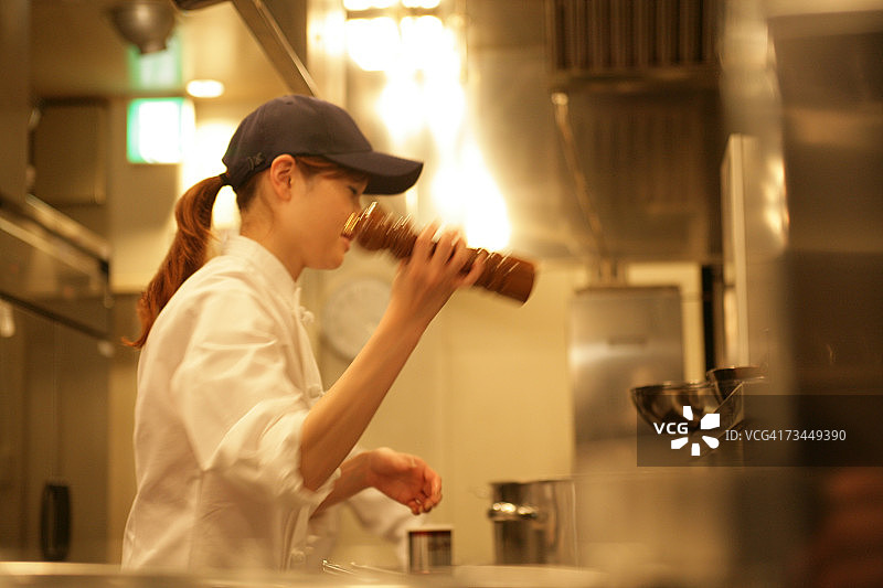 女厨师摇着胡椒研磨器的侧面轮廓图片素材