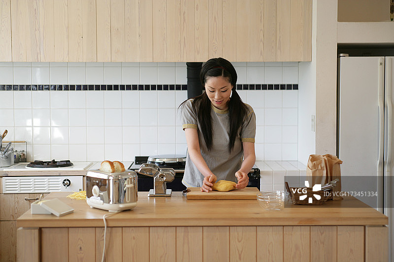 年轻女人在厨房揉面团图片素材