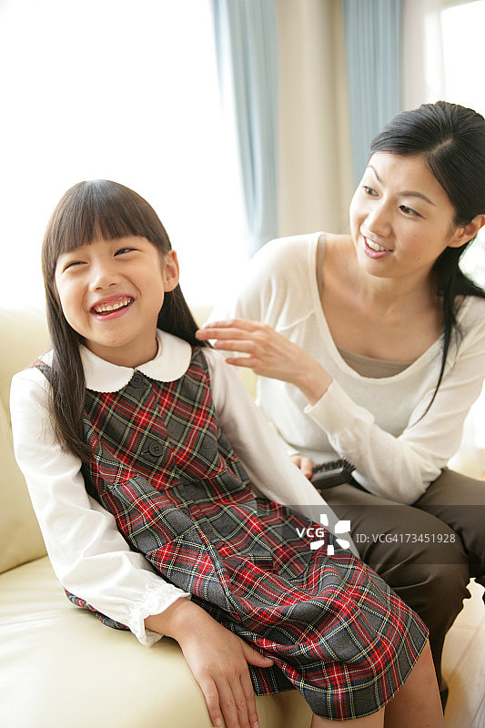 中年妇女拿着发刷看着她的女儿图片素材