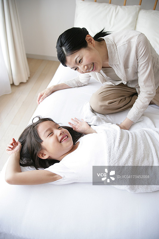 中年妇女和女儿在床上欢笑（高角度）图片素材