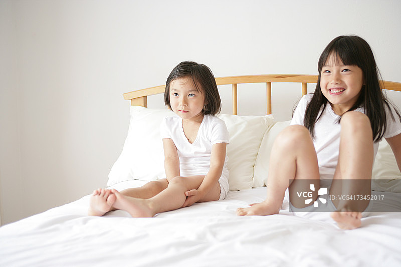 女孩和妹妹一起坐在床上图片素材