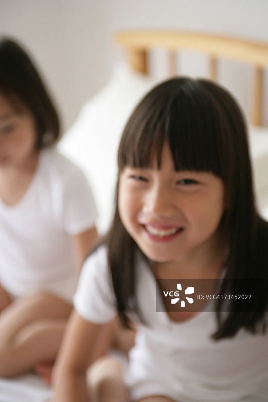 女孩和妹妹坐在床上微笑的肖像图片素材