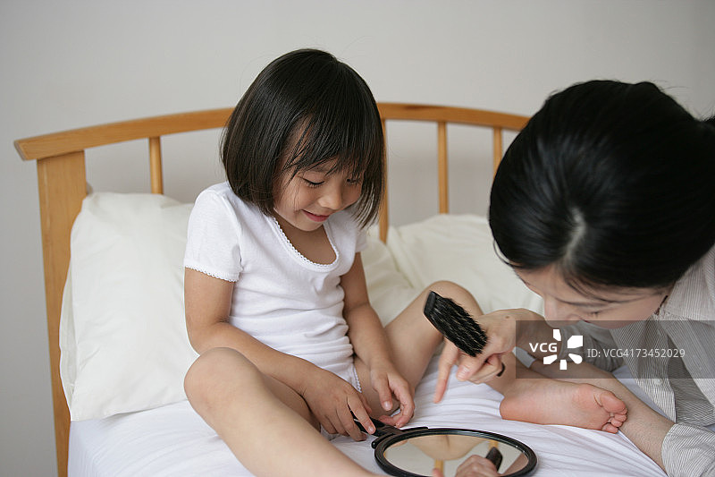 女孩和母亲在床上照镜子特写图片素材