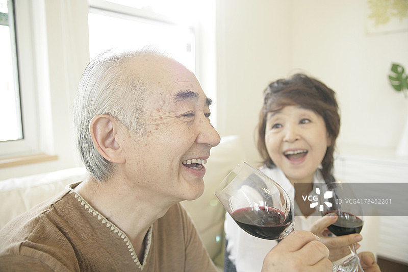 一对年长的夫妇手持红酒杯开怀大笑的特写图片素材