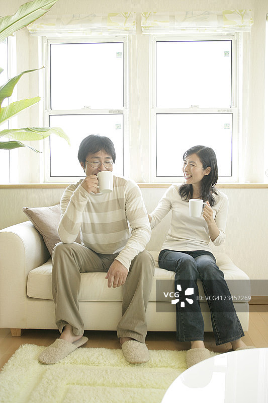 中年夫妇坐在沙发上喝咖啡图片素材