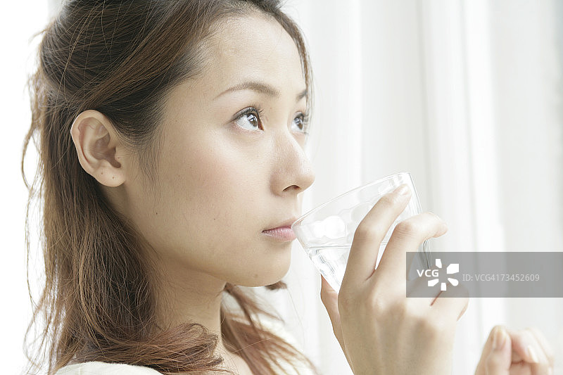 年轻女人喝一杯水的特写图片素材