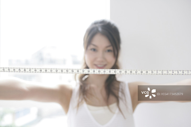 伸开双臂拿着卷尺的年轻女子肖像图片素材
