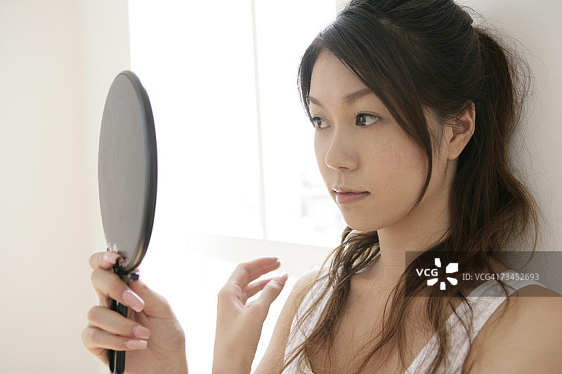 照着镜子思考的年轻女人特写图片素材