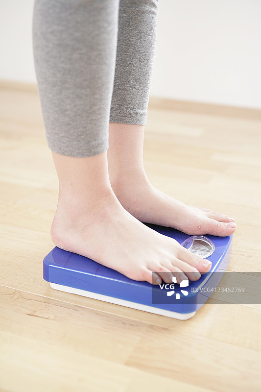 女人站在体重秤上的脚部低角度视图图片素材