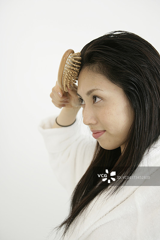 年轻女子梳头的侧面轮廓图片素材
