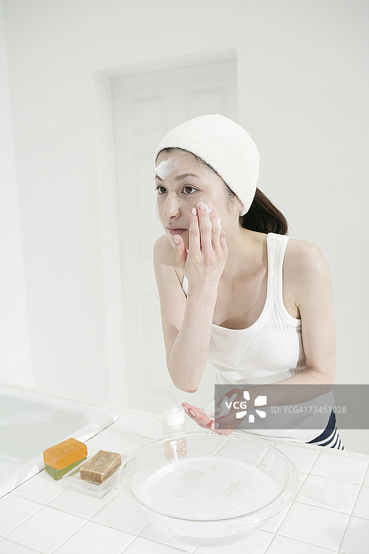 在脸上涂抹保湿霜的年轻女子特写图片素材