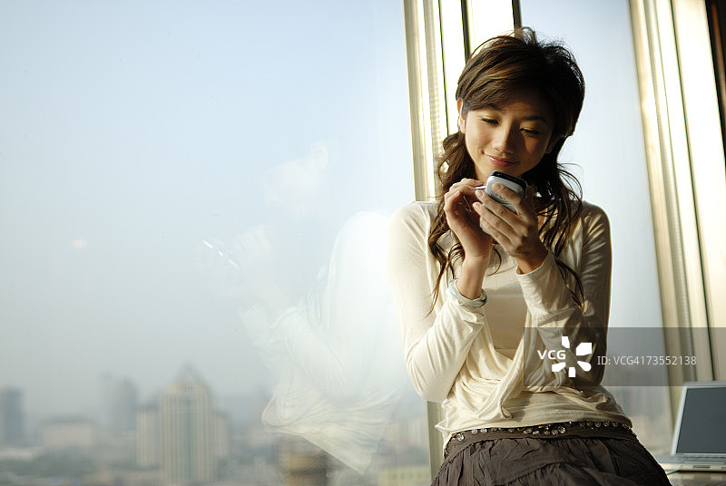 年轻女人在窗边使用掌上电脑微笑图片素材