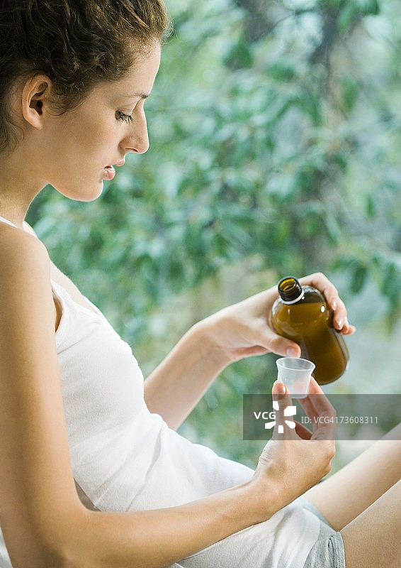 手持止咳糖浆瓶的女人图片素材
