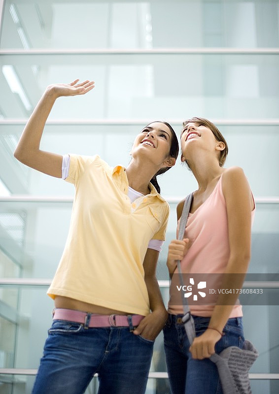 两个十几岁的女孩抬头看，一个在挥手图片素材