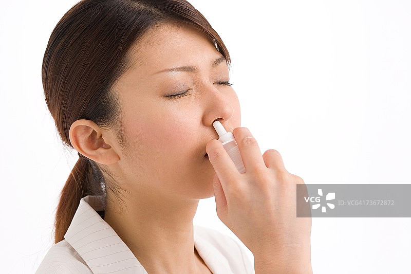 年轻女子使用鼻腔喷雾图片素材