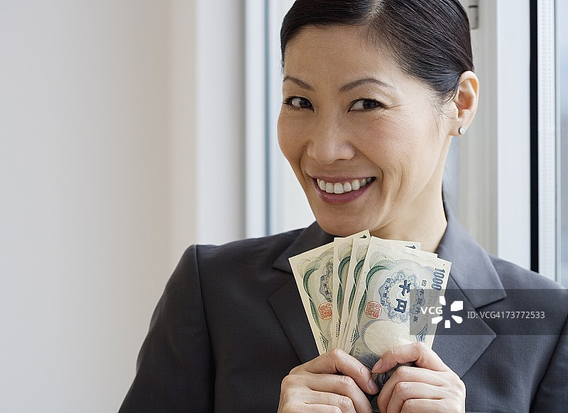 中年亚洲女商人拿着日元钞票图片素材