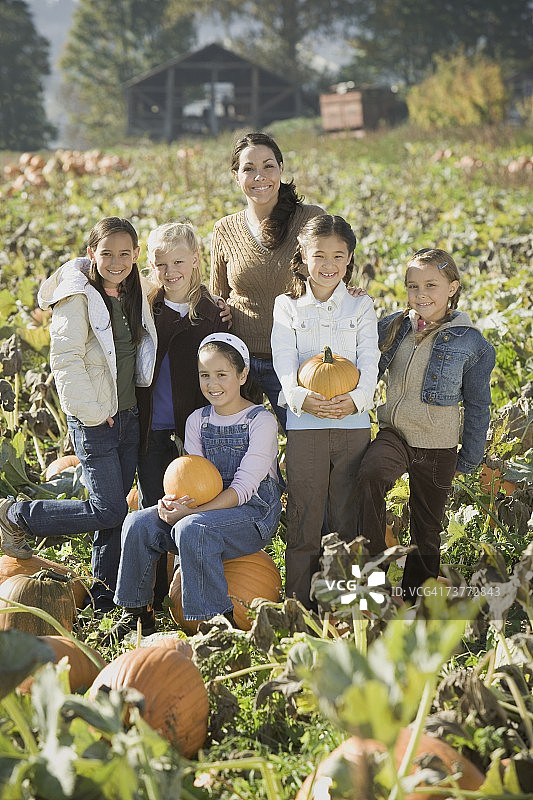在南瓜地里和一群孩子在一起的西班牙裔女人图片素材