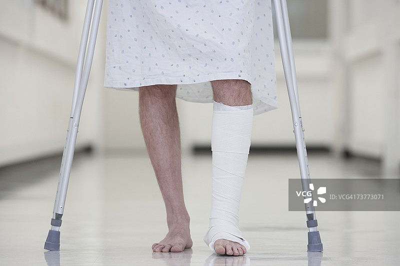 腿部骨折的男子在医院里拄着拐杖行走图片素材