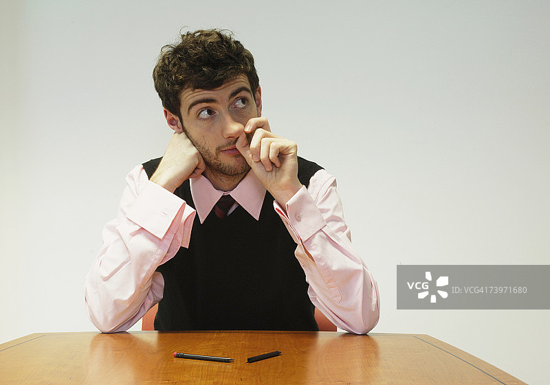 商人在会议桌旁抠鼻子图片素材