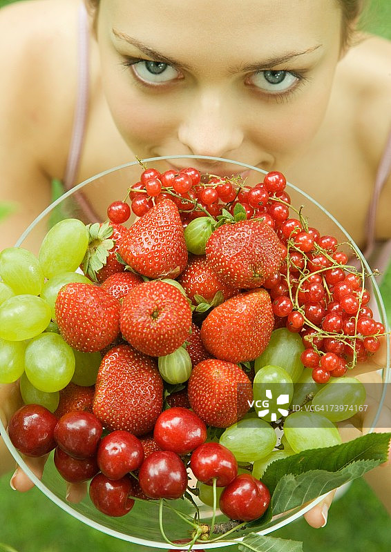 手持一碗水果对着镜头微笑的女人图片素材