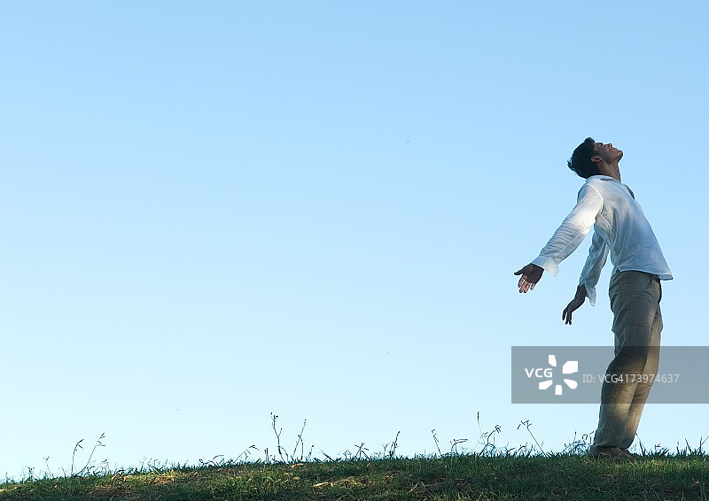 男人站在户外，手臂和头向后仰图片素材