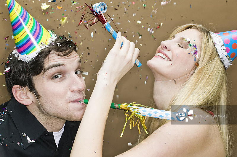 戴着派对帽，吹着吹风机的情侣图片素材