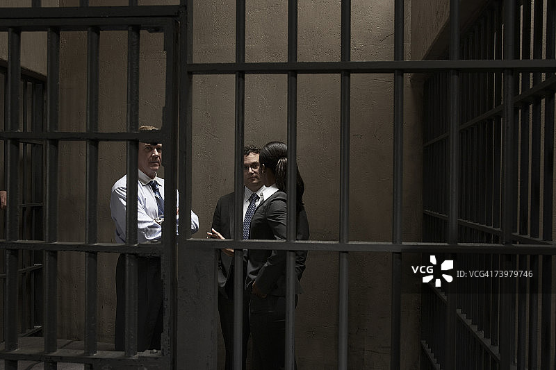 女人和两个男人在监狱牢房里交谈图片素材
