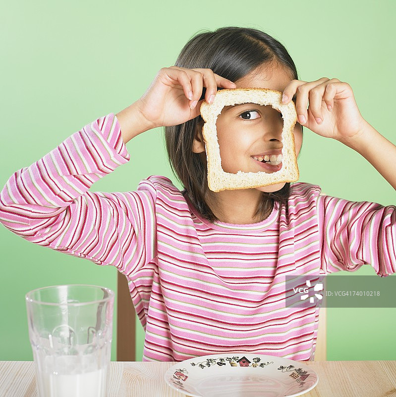 正在透过面包片上的洞看东西的西班牙裔女孩图片素材