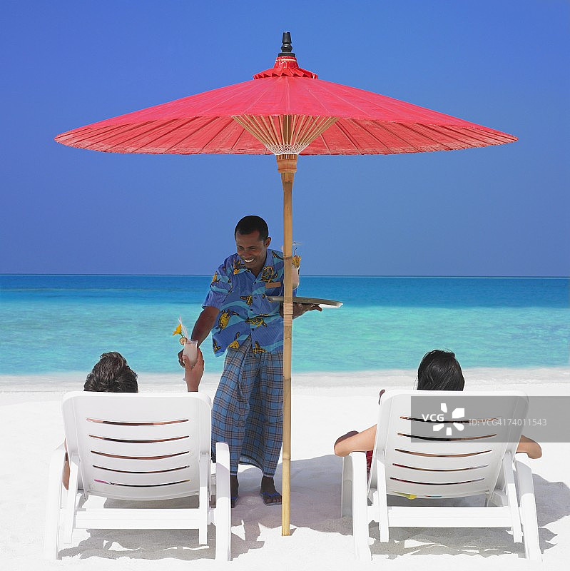 马尔代夫男人在海滩为夫妇提供饮品图片素材
