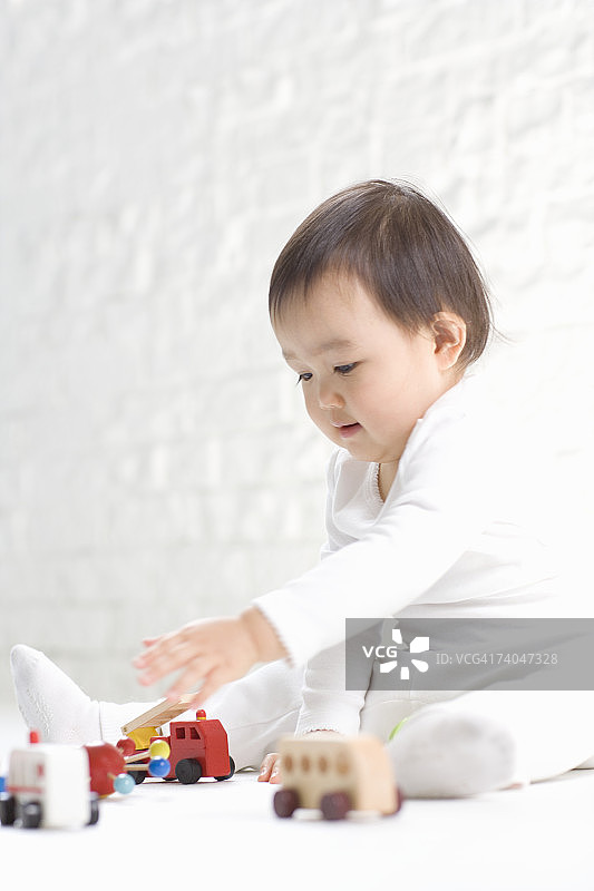 （15-18个月）在影棚玩木制玩具火车的女宝宝图片素材