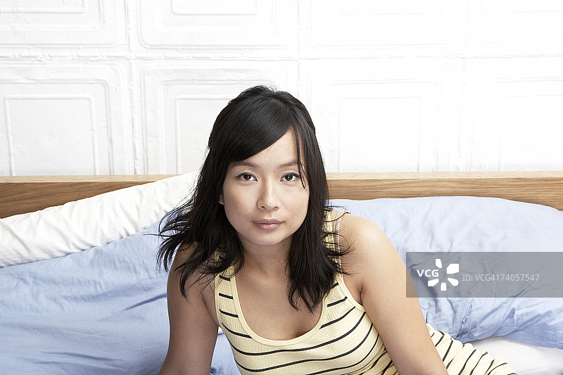 身穿条纹连衣裙坐在床上的年轻女子特写图片素材