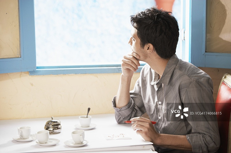 男人在纸巾上绘画，并看向窗外图片素材