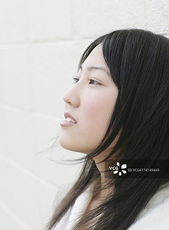 站在墙边看向远方的日本年轻女子图片素材