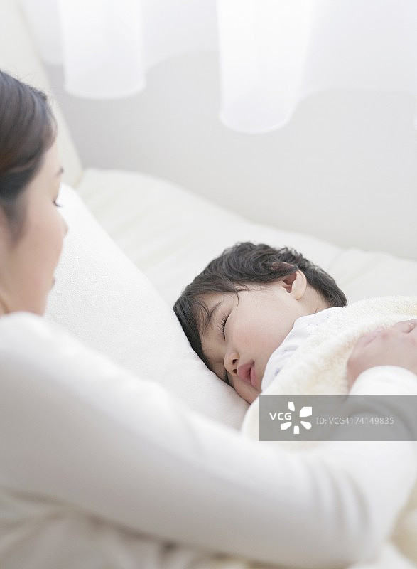 手放在熟睡男孩身上的日本女人图片素材