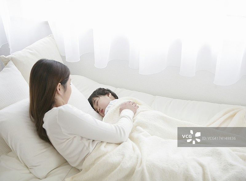 手放在熟睡男孩身上的日本女人图片素材