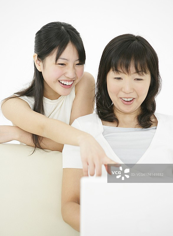日本年轻女子和母亲看笔记本电脑微笑图片素材