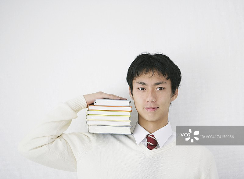 肩扛书本微笑的日本年轻学生图片素材