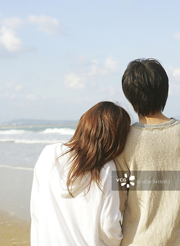 在海滩上手挽手的日本年轻夫妇图片素材