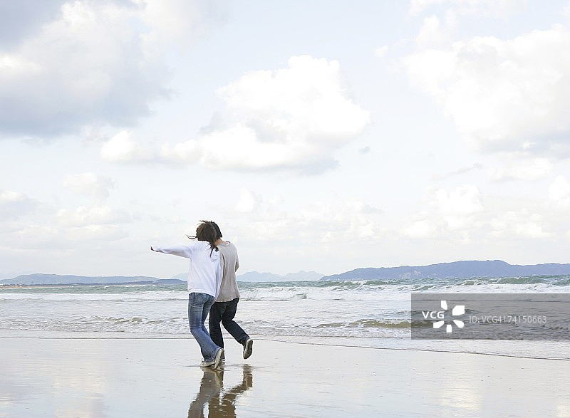 在沙滩上牵手行走的日本年轻夫妇图片素材
