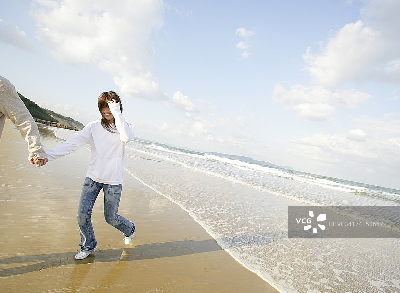 在海滩上奔跑的日本年轻夫妇图片素材