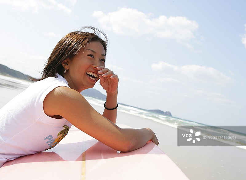 在海滩上拿着长板的日本冲浪女孩图片素材