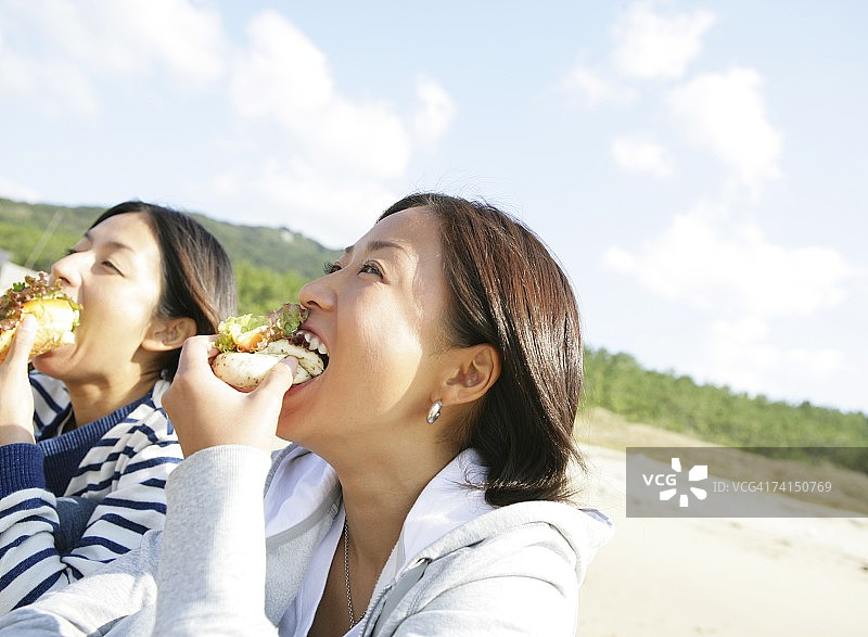 在海滩上吃三明治的冲浪女孩图片素材