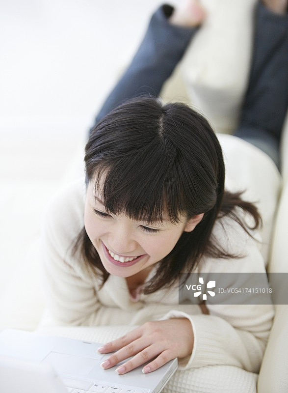 使用笔记本电脑并微笑的日本女人图片素材